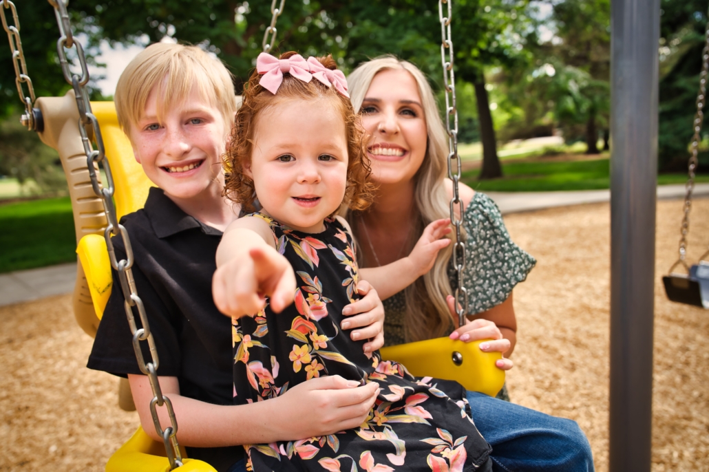 A woman and her two children on a swingset